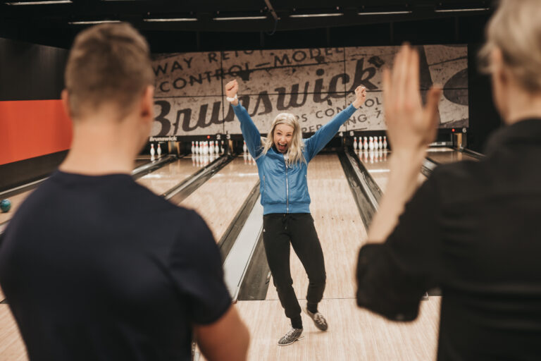 a woman cheering after throwing a bowling ball