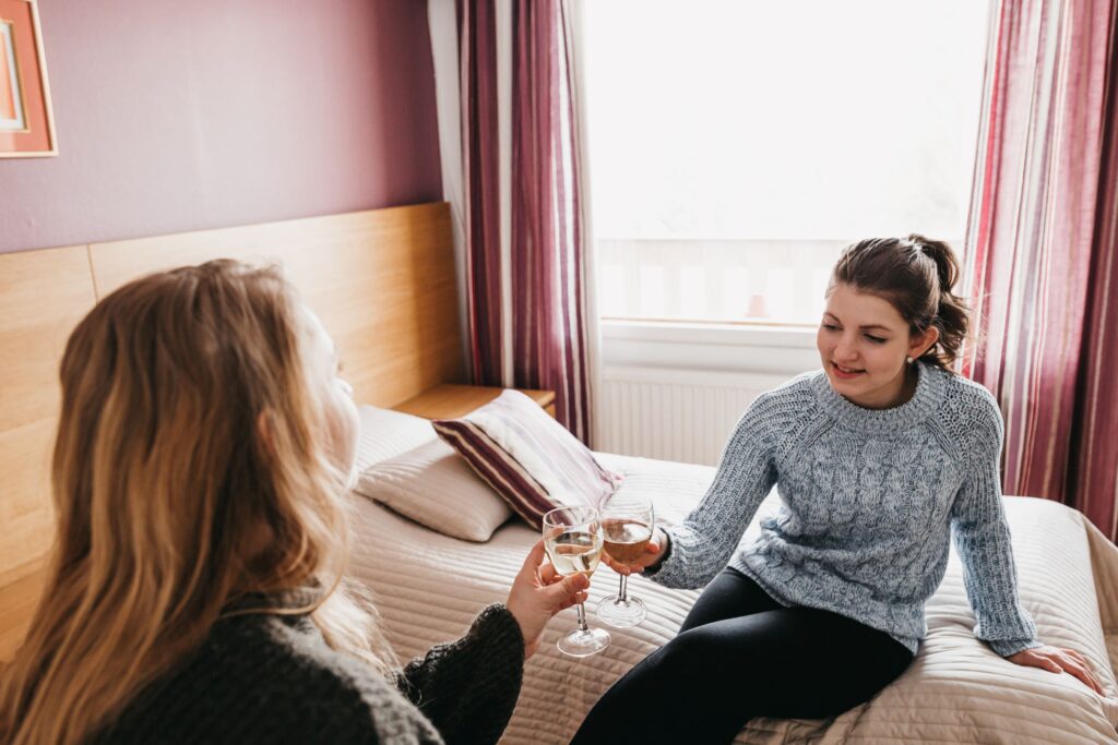 two young women toasting in a hotel room