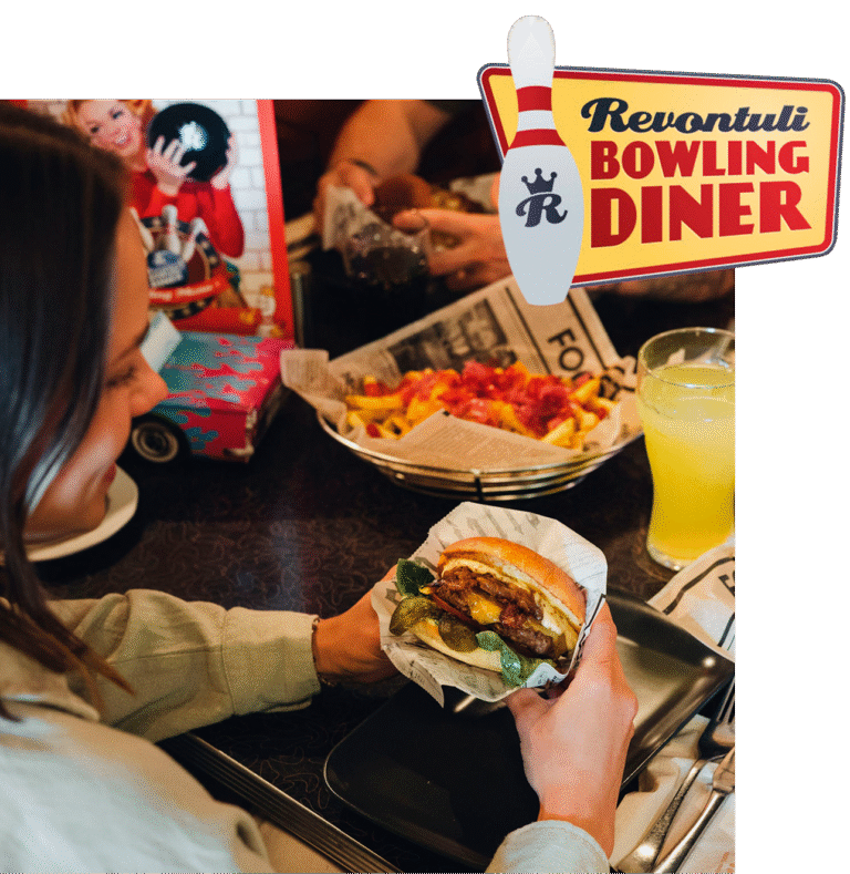 nainen syö hampurilaista bowling dinerissa