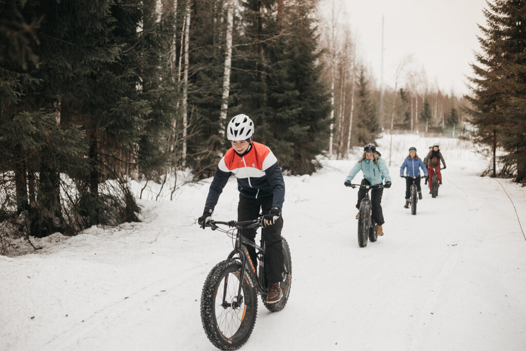 group of young people fatbiking in winter