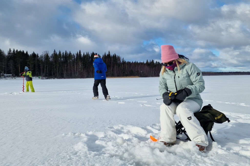 three people ice fishing in lake virmas