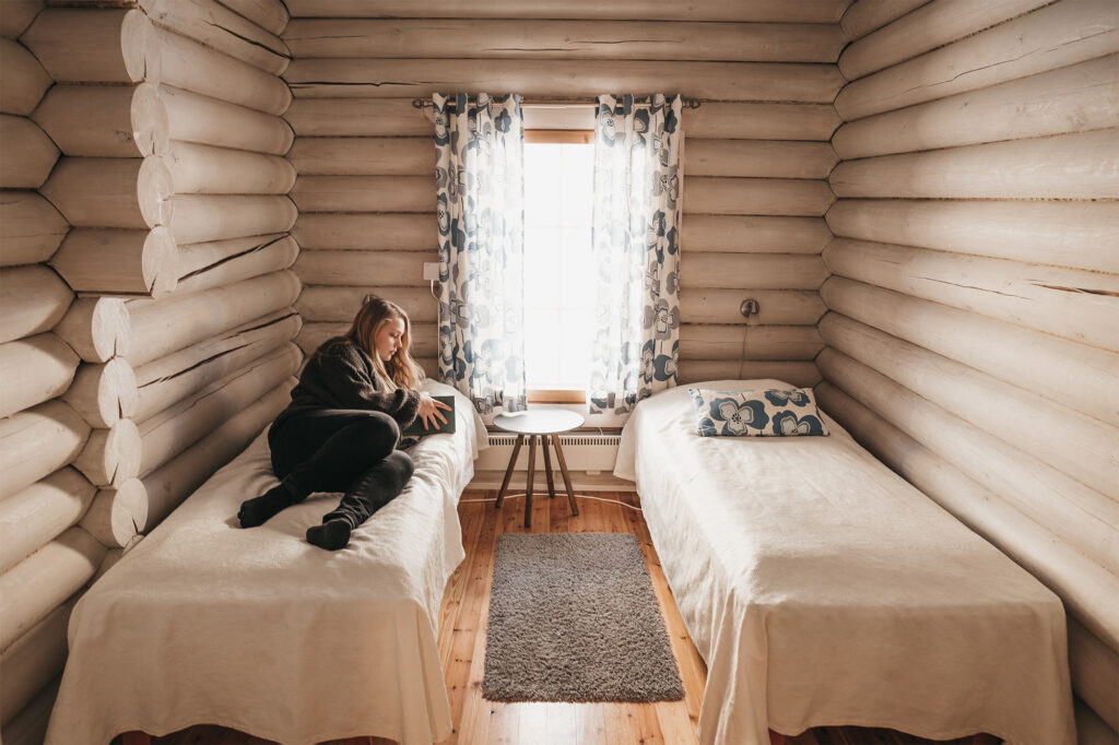 young woman relaxing on a bed in cabin isokarhu